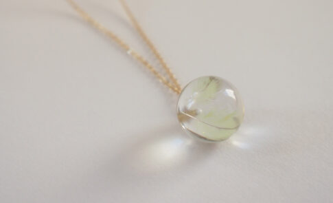 インコの羽根をレジンで球体に封入し、ゴールドチェーンを付けたメモリアルネックレス